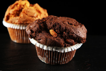 Chocolate muffin and nut muffin, homemade bakery on dark background.