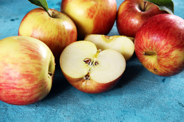 Ripe red apples with leaves on wooden background.