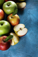 Ripe red apples with leaves on wooden background.