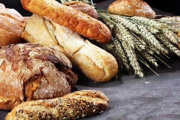 Different kinds of bread and bread rolls on board from above. Kitchen or bakery