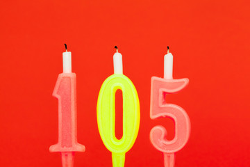 Fototapeta na wymiar Colorful burning birthday candle on red background