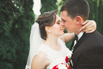 Newly married couple running and jumping in park while holding hands