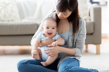 family and motherhood concept - happy smiling young asian mother with little baby at home