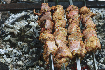 Marinated shashlik from pork preparing on a bonfire charcoal. Popular eastern dish can be called Shish kebab