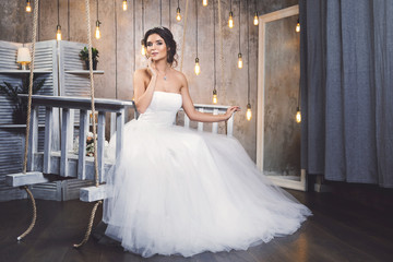 Young happy bride wearing beautiful lush dress in the room with a lot of light bulbs