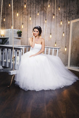 Young happy bride wearing beautiful lush dress in the room with a lot of light bulbs