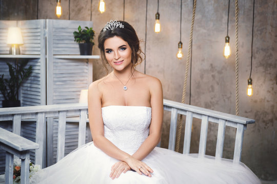 Young happy bride wearing beautiful lush dress in the room with a lot of light bulbs