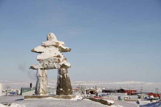 Inukshuk or Inuksuk landmark covered in snow found on a hill in the community of Rankin Inlet, Nunavut in February