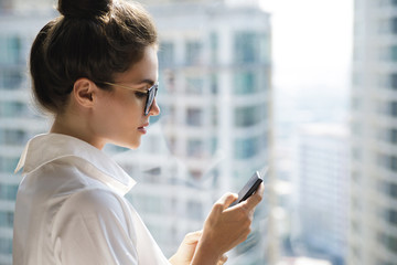 Young businesswoman using smartphone in her office