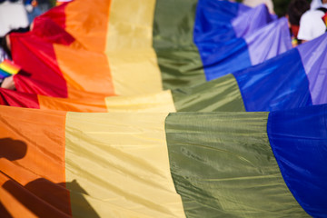 people holding giant rainbow flag at pride parade - LGBT symbol