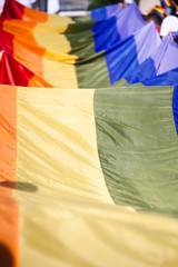 people holding giant rainbow flag at pride parade - LGBT symbol