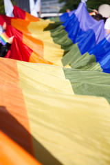 people holding giant rainbow flag at pride parade - LGBT symbol