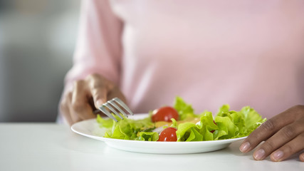 Fototapeta na wymiar Woman eating vegetable salad close-up, healthy eating habits, high-fiber dieting