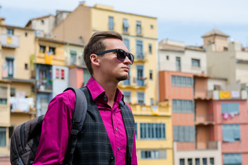 A young man, tourist, stands on the river bank Onyar in Girona, Spain