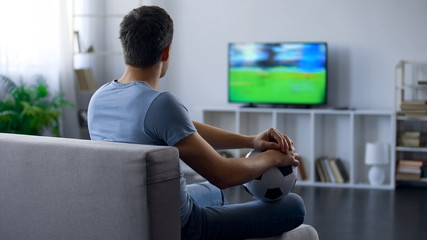 Fan of soccer team watching game on tv home, thinking about match result