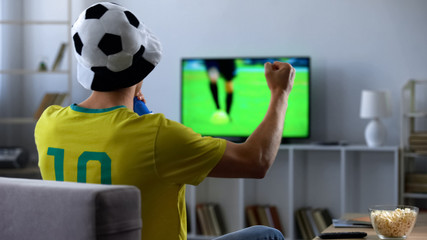 Brazilian fan actively cheering favourite football team watching match on tv