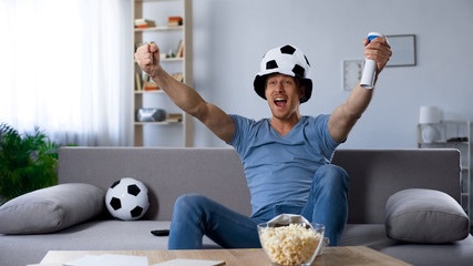Ardent football supporter in fan hat rejoicing to scored penalty kick, victory