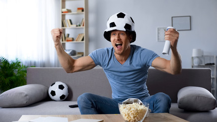 Football supporter in fan hat sincerely rejoicing to scored kick at last minutes