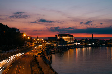 Fototapeta na wymiar Kiev Kyiv city, the capital of Ukraine at night with beautiful sunset clouds, colorful illumination and reflection in Dnieper Dnipro river. Long exposure traffic light.