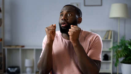 Excited afro-american football fan worrying about national team in final game