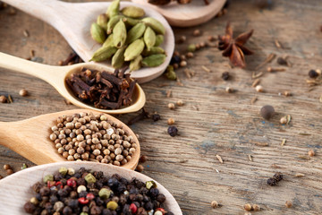 Colourful aromatic various spices for cooking on old wooden board, close-up, flat lay, shallow depth of field.