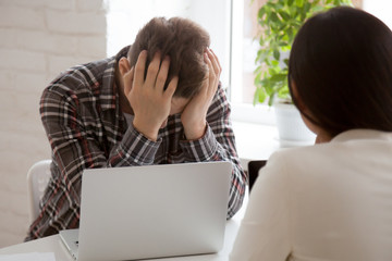 Frustrated male worker holding head in hands upset with business collapse, depressed about money...