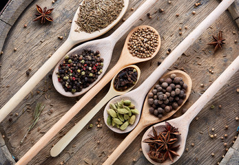 Colourful aromatic various spices for cooking on old wooden board, close-up, flat lay, shallow depth of field.