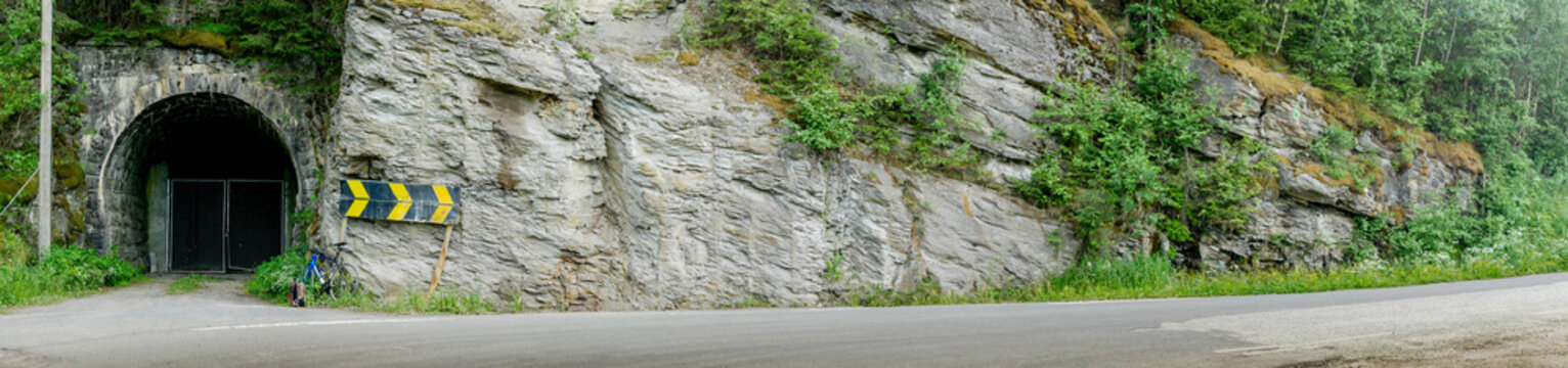 Panorama of road with old tunnel and mountain wall