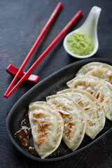 Potstickers or fried korean dumplings in a cast-iron serving pan, selective focus, closeup, vertical shot