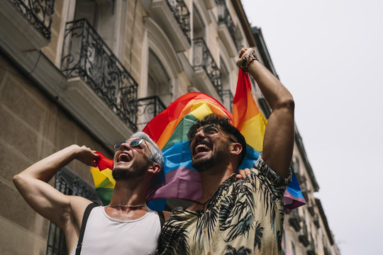 Couple boys with gay pride flag on the street of Madrid city
