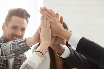 Close up of excited colleagues giving high five, celebrating shared goal achievement or win, performing team building, showing unity, workers greeting with successful project, good business results