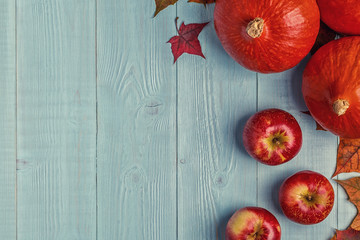 Autumn background with colored leaves and pumpkins on wooden background.