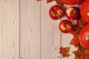 Autumn background with colored leaves and pumpkins on wooden background.