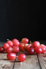 Placer of pink grapes on a wooden table on a black background. Rustic style