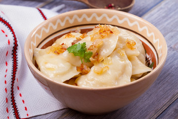 Dumplings, filled with mashed potato - vegetarian dish. Varenyky, vareniki, pierogi, pyrohy in a bowl on wooden table. horizontal