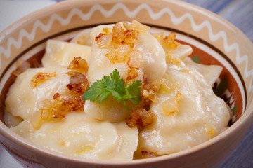 Dumplings, filled with mashed potato - vegetarian dish. Varenyky, vareniki, pierogi, pyrohy in a bowl on wooden table. horizontal