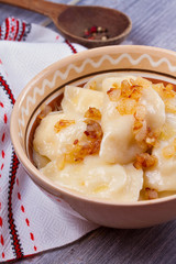 Dumplings, filled with mashed potato - vegetarian dish. Varenyky, vareniki, pierogi, pyrohy in a bowl on wooden table. vertical