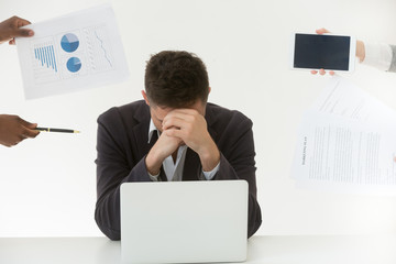 Depressed male employee in despair exhausted by excessive workload and annoying colleagues, tired worker feeling fatigue suffering from work stress and headache trying to control emotions.