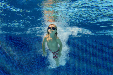 Smiling boy swimming underwater in pool