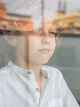 Sad little boy looking through glass