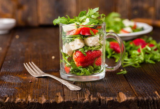 Fresh vegetable strawberry salad in glass jar on natural rustic desk.