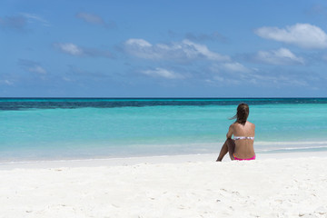 Obraz premium Junge Frau sitzend an weißem Sandstrand Blick zum Meer