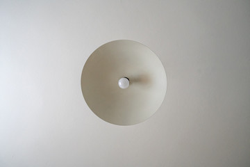 Round chandelier with a light bulb on the ceiling, a bottom view of the lamp