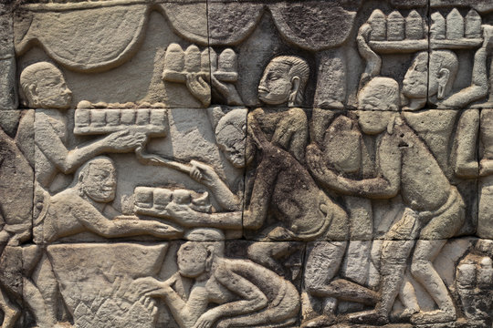 Ancient temple stone carved bas-relief in Angkor Wat. Cooking people bas-relief closeup. Angkor Wat complex Bayon temple
