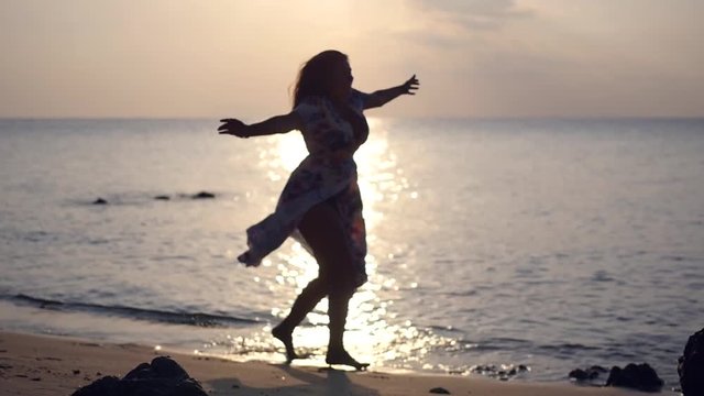 Elegant kopeck with large breasts, feel freedom, spinning and jumping, standing on the sandy beach at sunset. HD, 1920x1080, slow motion