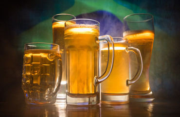 Creative concept. Beer glasses on table at dark toned foggy background with blurred view of flag of Brazil. Support your country with beer concept.