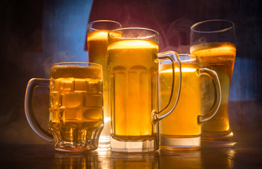 Creative concept. Beer glasses on table at dark toned foggy background with blurred view of flag of...