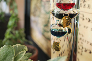 Galileo thermometer with colorful glass bubbles in liquid giving indoor temperature