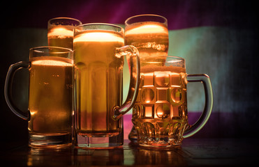 Creative concept. Beer glasses on table at dark toned foggy background with blurred view of flag of Spain. Support your country with beer concept