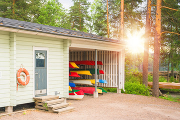 Collection of vibrant colorful plastic recreational canoe and kayaks stored storage rack, side view © Bonsales